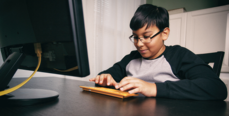 Tackle challenges A young kid working at a computer to solve a problem