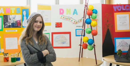 Inspire others A young girl standing in front of a science fair board