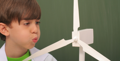 Learn by doing A young boy blowing on a model windmill